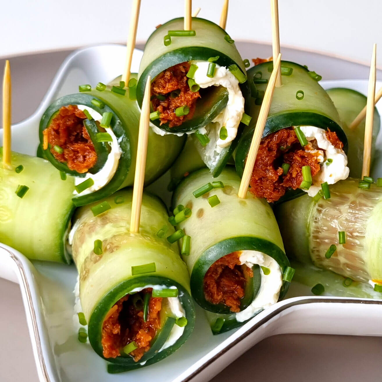 Borrelhapjes gemaakt van plakjes komkommer met kruidenroomkaas en zongedroogde tomaten tapenade