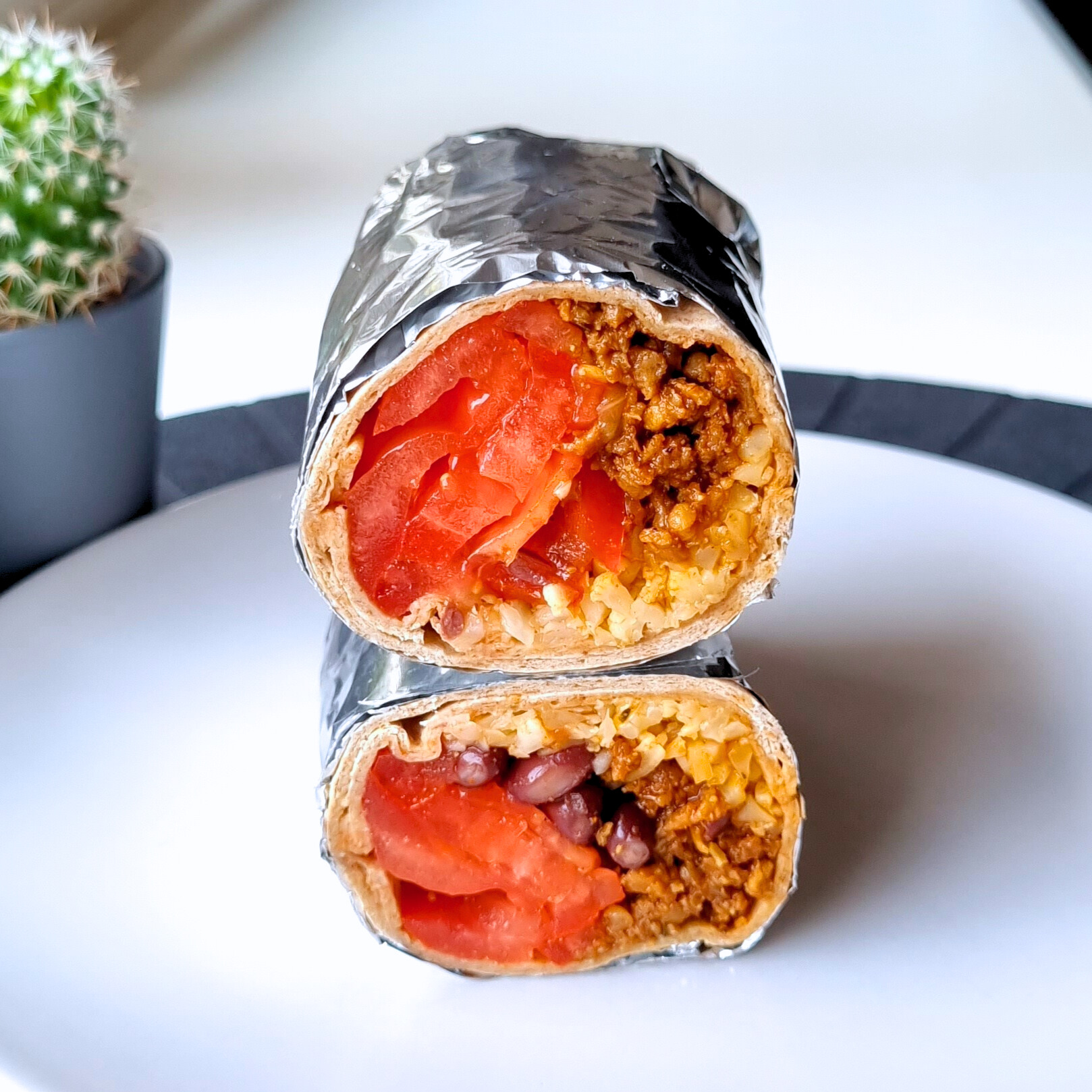 Recept voor eiwitrijke vegan burrito's. Trostomaten, zwarte bonen, bloemkool en gekruid sojagehakt in een volkoren tortilla