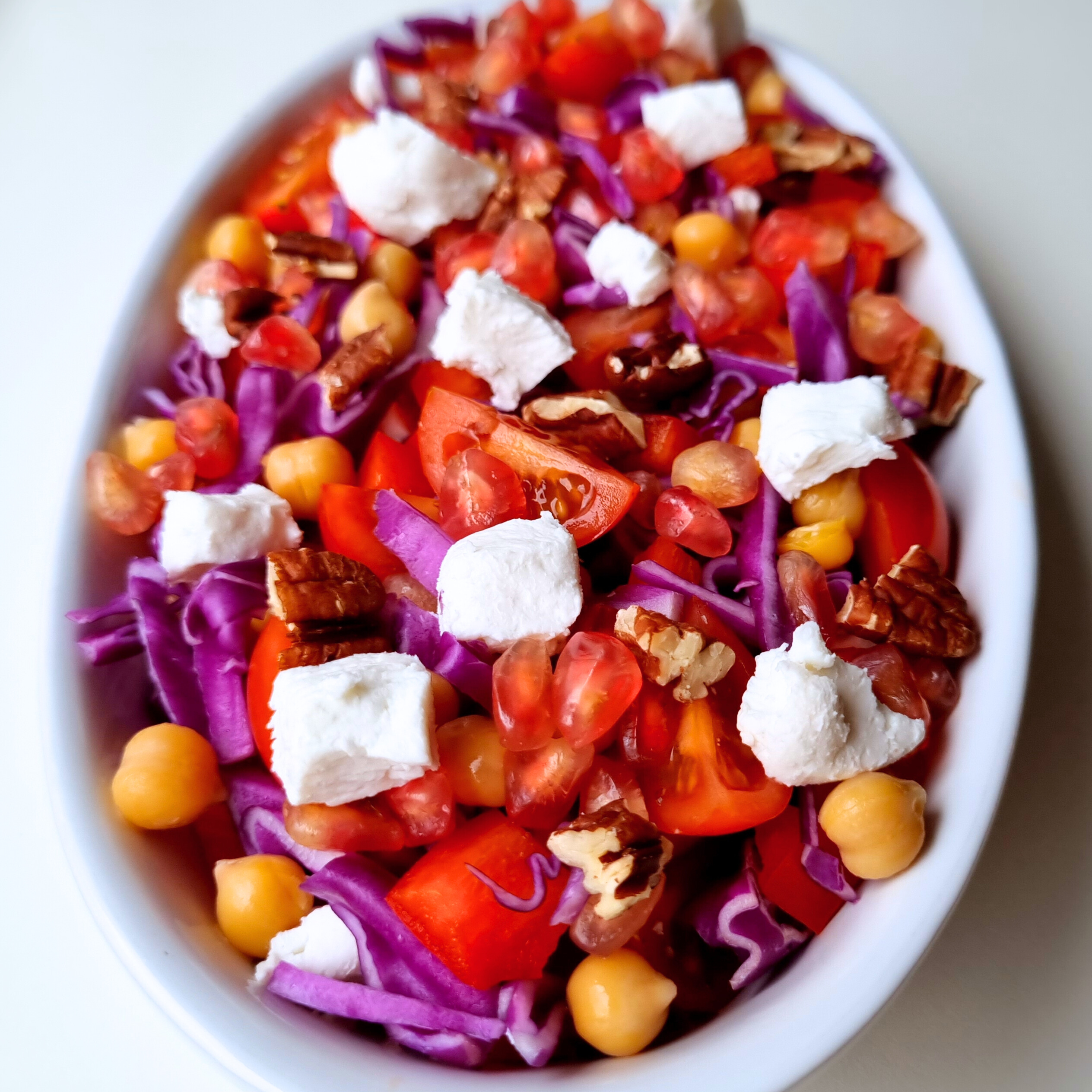 Prachtige vegetarische salade met geitenkaas, granaatappel, kikkererwten, pecannoten, paarse spitskool, paprika en tomaat