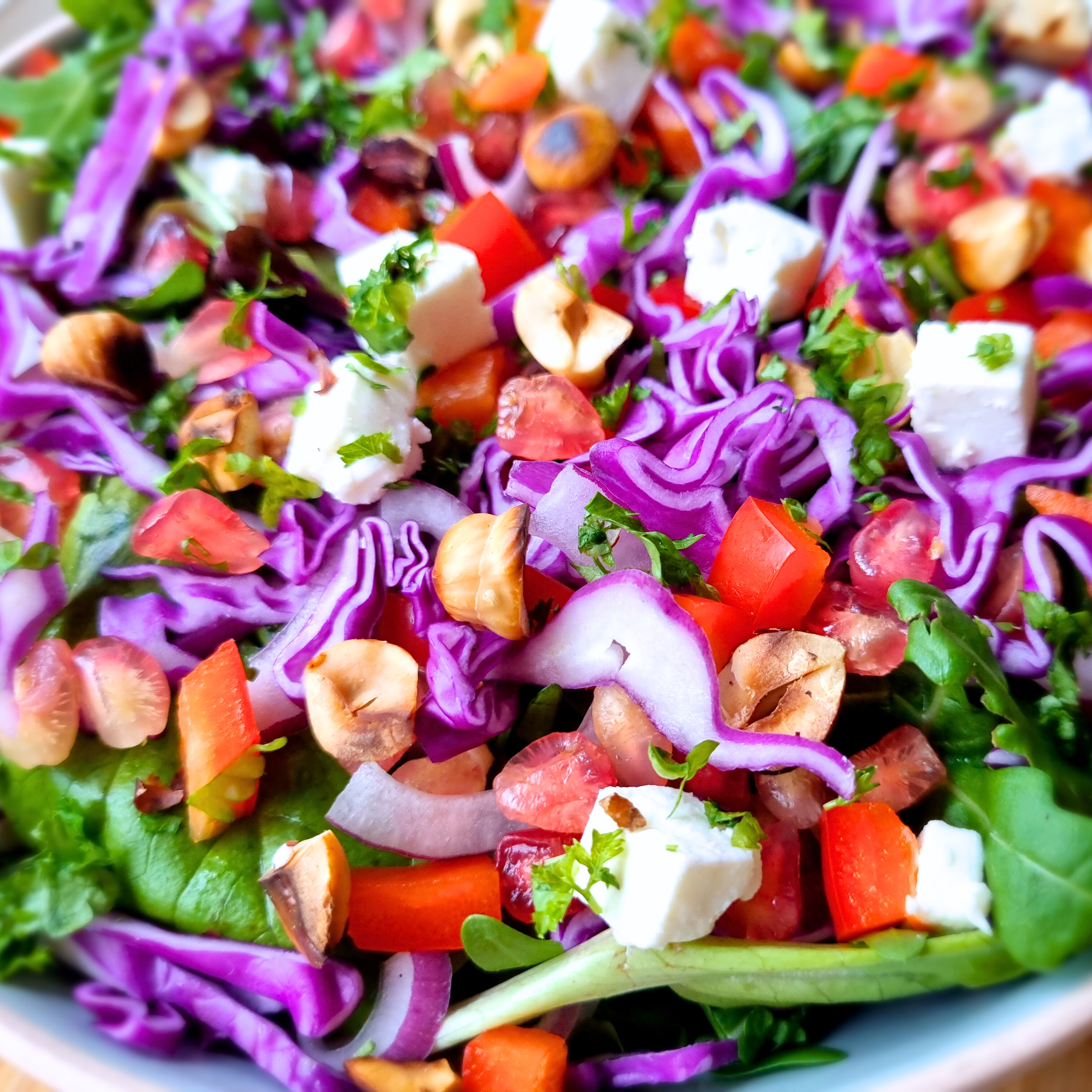 Salade met sla, paarse spitskool, paprika, granaatappel, feta, rode ui, geroosterde hazelnoten en peterselie