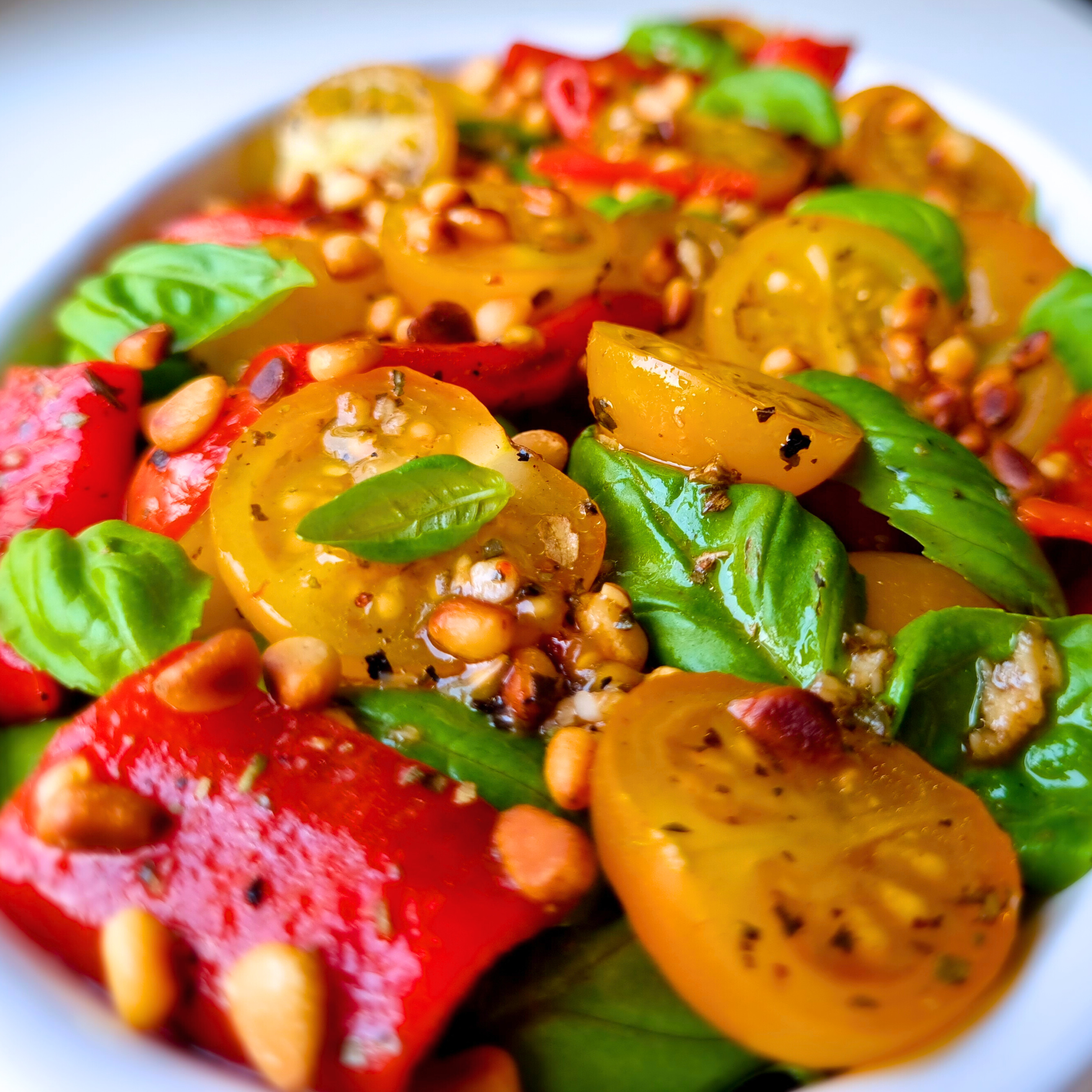 Heerlijke zomerse Mediterrane salade met geroosterde rode puntpaprika, gele cherrytomaatjes, pijnboompitten en basilicum