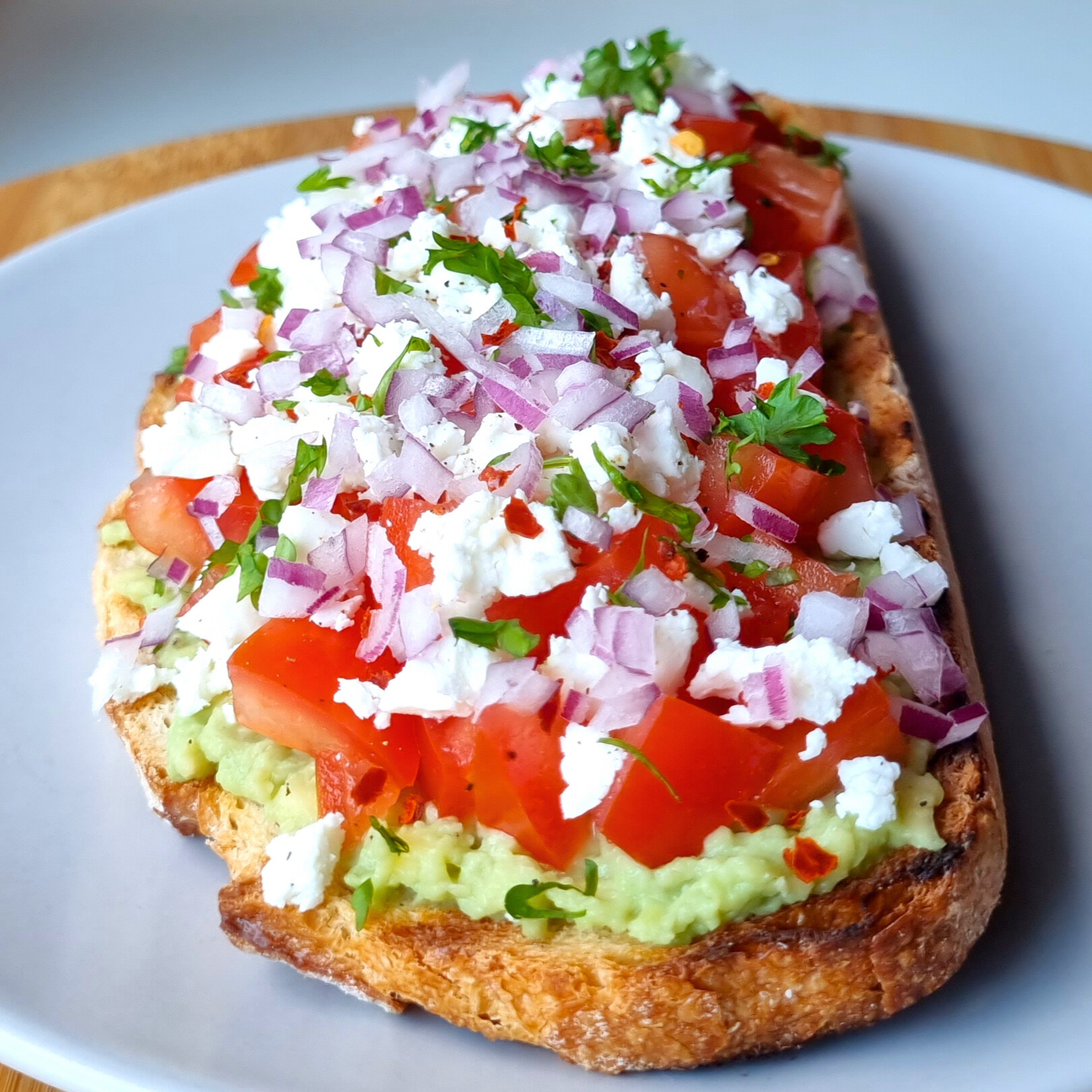 Avocadotoast met tomaat, feta, rode ui & chilivlokken