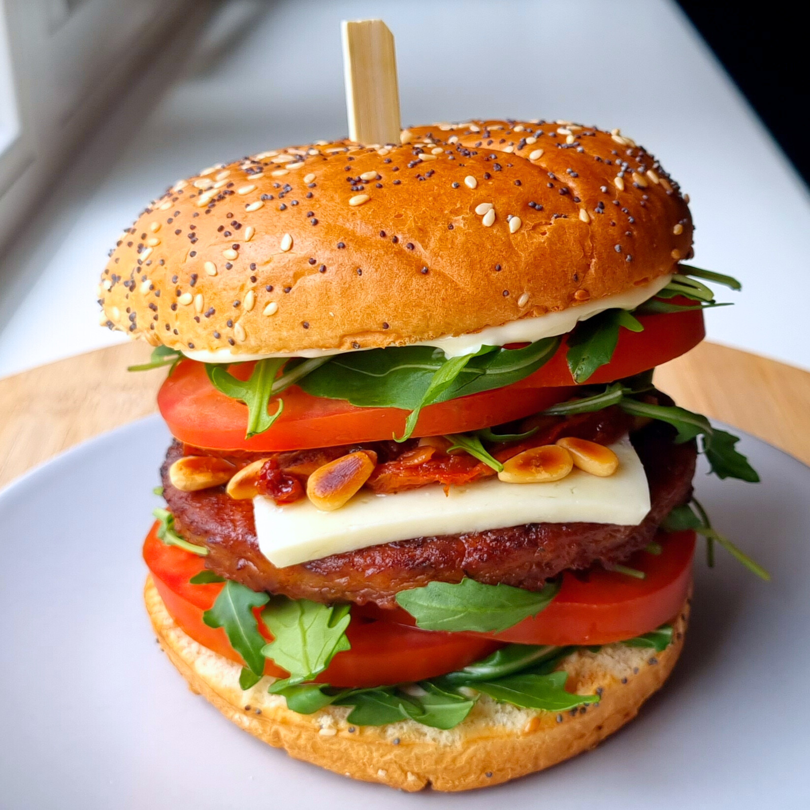 Verrukkelijke vegaburger met tomaat, rucola sla, geroosterde pijnboompitjes, pecorino en zongedroogde tomaat