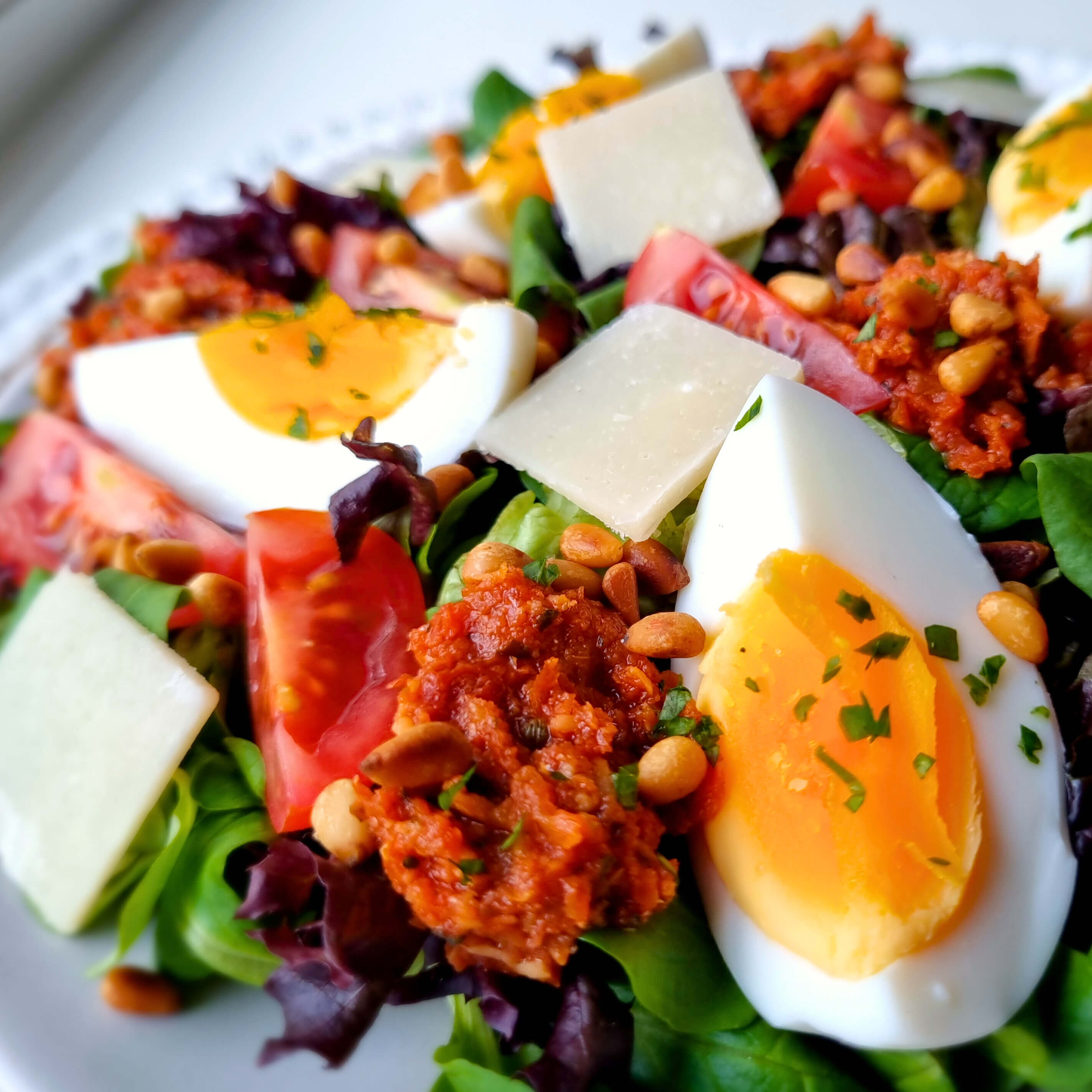 Zalige Mediterraanse salade met sla, zoete mini Romatomaat, gekookte eieren, Parmigiano, zongedroogde tomaten tapenade en geroosterde pijnboompitten