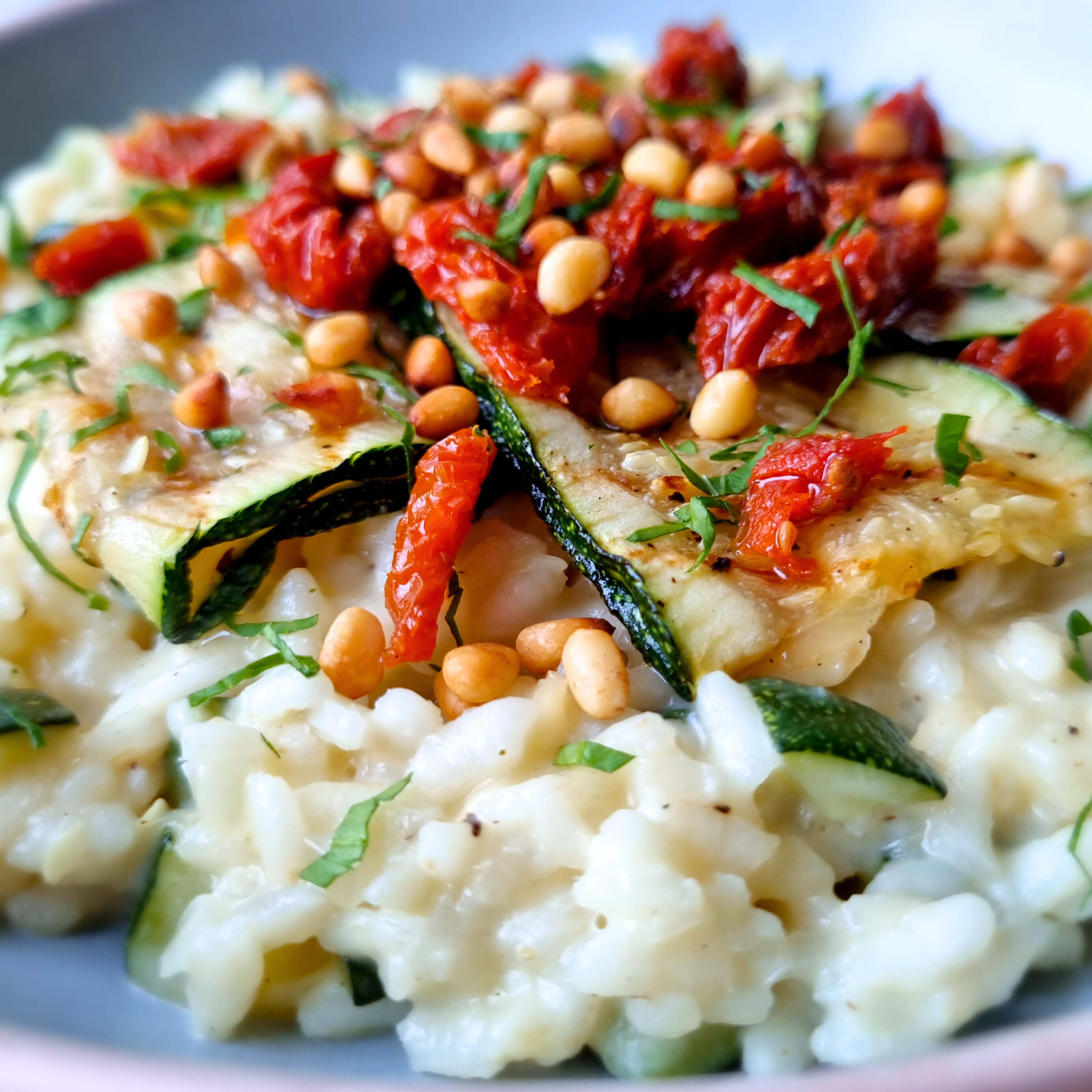 Makkelijk vegetarisch hoofdgerecht: courgetterisotto met slagroom, oude kaas, zongedroogde tomaat en pijnboompitten